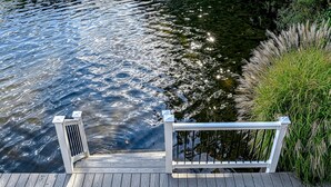 Un muelle de madera que se extiende sobre el agua, con barandilla y un pequeño respiradero.