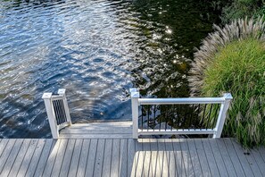 A wooden dock extending over water with a railing and a small vent. - Lakefront Family Home in Gated Community With Swimming Area & Dock - Dogs OK (Bumpass)