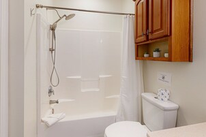 Un baño con ducha, inodoro y estante con plantas pequeñas.