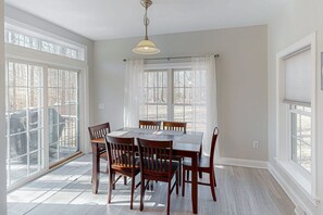 A dining room with a table and chairs, large windows, and a ceiling light. - Fun & Relaxing Getaway With 2 Game Rooms, Fire Pits, Deck, & More (Orange)