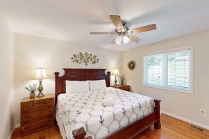 A bedroom with a wooden bed, two bedside tables with lamps, a ceiling fan, a decorative wall piece, and a window with blinds. - Spacious pet Friendly House W/private Pool Table, Ping Pong Table & Free Wifi (Bumpass)