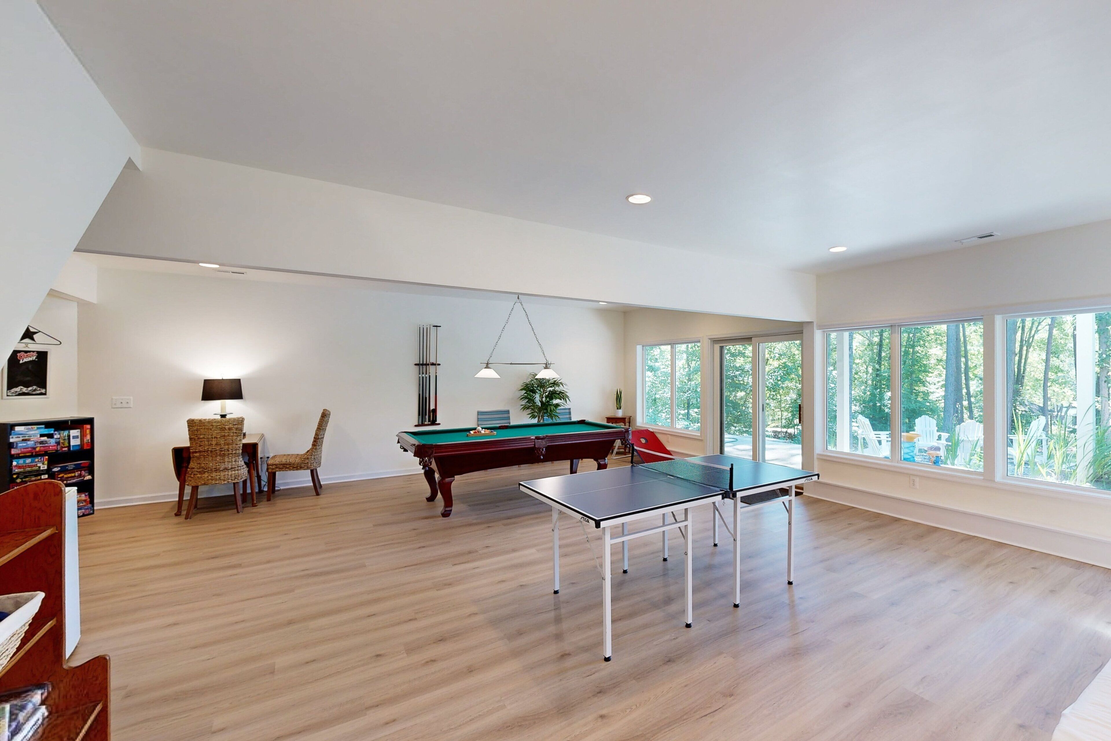 A spacious room with a pool table, a ping pong table, and a billiards table.