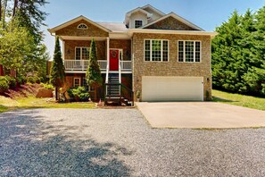 A two-story house with a stone facade, a front porch, and a garage. - Family-friendly Waterfront Retreat With Game Room, EV Charger, & More! (Bumpass)
