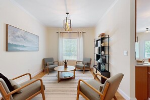 A living room with a round coffee table, four armchairs, a bookshelf, and a painting on the wall. - Family-friendly Waterfront Retreat With Game Room, EV Charger, & More! (Bumpass)