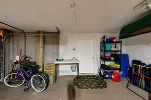 A garage with a bicycle, a workbench, a door, and shelves with various items. - Family-friendly Waterfront Retreat With Game Room, EV Charger, & More! (Bumpass)