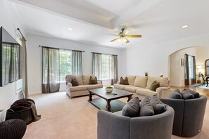 A spacious living room with two sofas, a coffee table, and a ceiling fan. - Family-friendly Waterfront Retreat With Game Room, EV Charger, & More! (Bumpass)