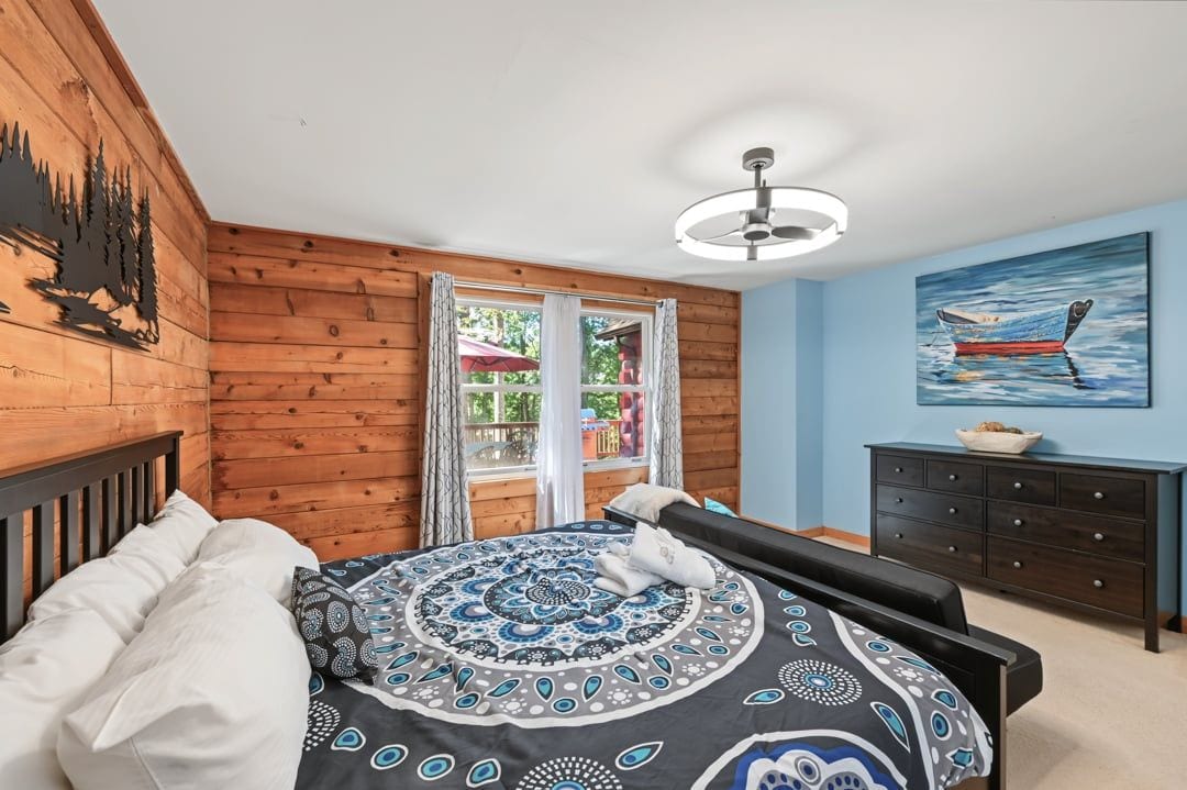 Un dormitorio con cama, un banco, un aparador y un cuadro en la pared.