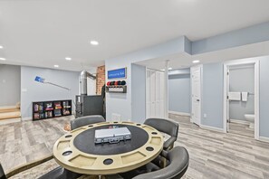 A room with a round table, chairs, a bookshelf, a fireplace, and a bathroom in the background. - Lakefront Home With Boat Mooring, Deck, hot Tub, Game Room & Fast Wifi - Dogs OK (Bumpass)