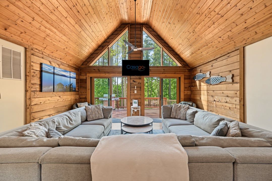 A cozy room with a wooden ceiling, a large window, and a sofa.