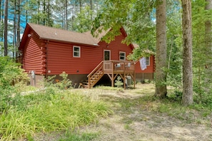 A red log cabin with a wooden deck and a staircase leading to a door. - Lakefront Home With Boat Mooring, Deck, hot Tub, Game Room & Fast Wifi - Dogs OK (Bumpass)