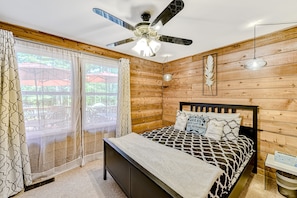 A bedroom with a bed, wooden walls, a ceiling fan, and a window with curtains. - Lakefront Home With Boat Mooring, Deck, hot Tub, Game Room & Fast Wifi - Dogs OK (Bumpass)