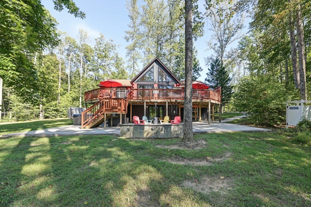 Une cabane dotée d’une terrasse, de meubles de jardin et d’une cheminée en pierre.