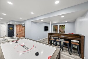 Una habitación con mesa de futbolín, dardo y televisor.