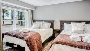Een slaapkamer met twee bedden, een plafondventilator, een raam met gordijnen en een nachtkastje.