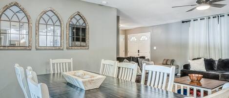 Un comedor con una mesa de madera oscura, sillas blancas y un cuenco de madera como centro de mesa.