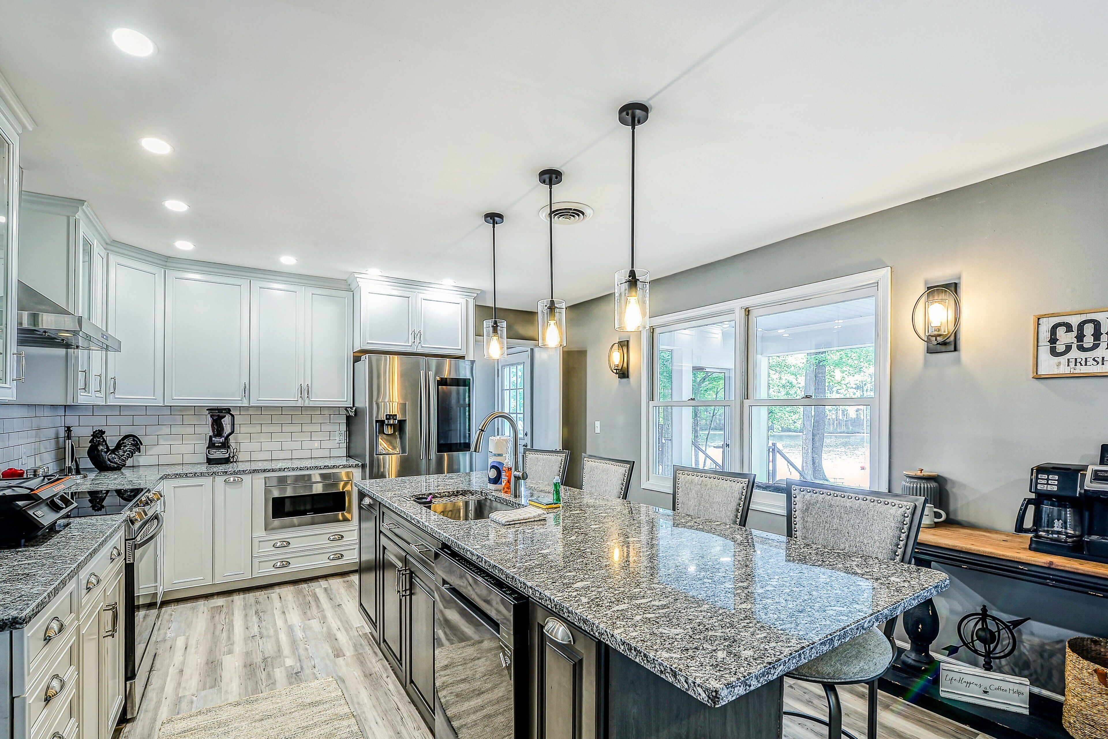 A modern kitchen with white cabinets, granite countertops, and stainless steel appliances.