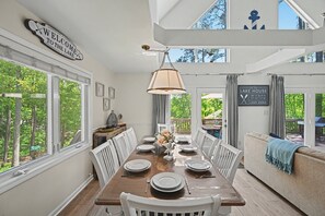 A dining area with a table set for six, a chandelier, and a view of the outdoors. - Lakefront - Brand-new hot Tub, Dock, Kayaks, Sup, Game Room & Firepit (Bumpass)