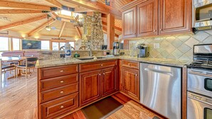 A spacious kitchen with wooden cabinets, stainless steel appliances, and a stone accent wall. - Huge Lakefront Home With A/c, Sunroom, Boat Ramp, Wifi,game Room, Deck, & Kayaks (Louisa)