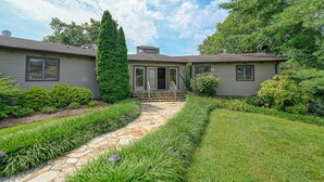 A two-story house with a stone pathway leading to the front door, surrounded by well-maintained greenery and a clear sky. - Huge Lakefront Home With A/c, Sunroom, Boat Ramp, Wifi,game Room, Deck, & Kayaks (Louisa)