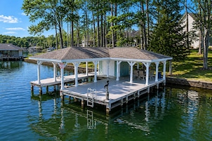 A covered dock with a seating area, a small boat, and a sign indicating a 15-minute wait.