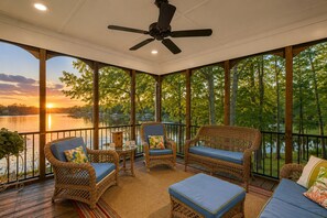 A covered outdoor deck with wicker furniture, a ceiling fan, and a view of a lake at sunset. - Lake Anna Waterfront Oasis w/ Firepit,boat Dock, dog Friendly (Mineral)