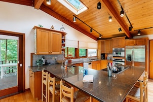 Una cocina moderna con armarios de madera, una isla grande, electrodomésticos de acero inoxidable y un tragaluz.
