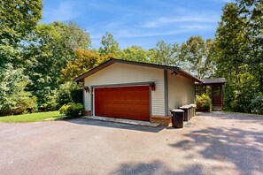 A single-story building with a garage, surrounded by trees and a clear sky. - Family Lake House With Deck, Private Dock/boathouse, Grill, Firepit, & Fast Wifi (Mineral)