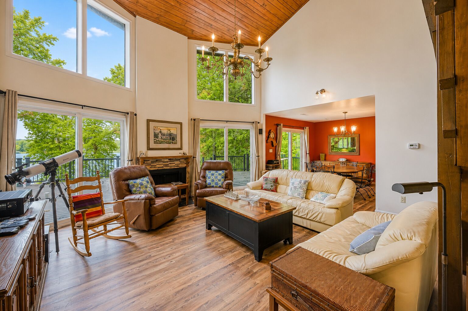 A spacious living room with a fireplace, leather chairs, a sofa, and a telescope.