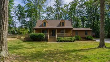 A two-story wooden house with a front porch, a small attached garage, and a well-maintained lawn.