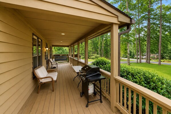 A covered porch with a grill, chairs, and a view of a green landscape. - Lake Anna Home on Large Corner lot With Kayaks, Paddleboard, Firepit & Grill (Bumpass)