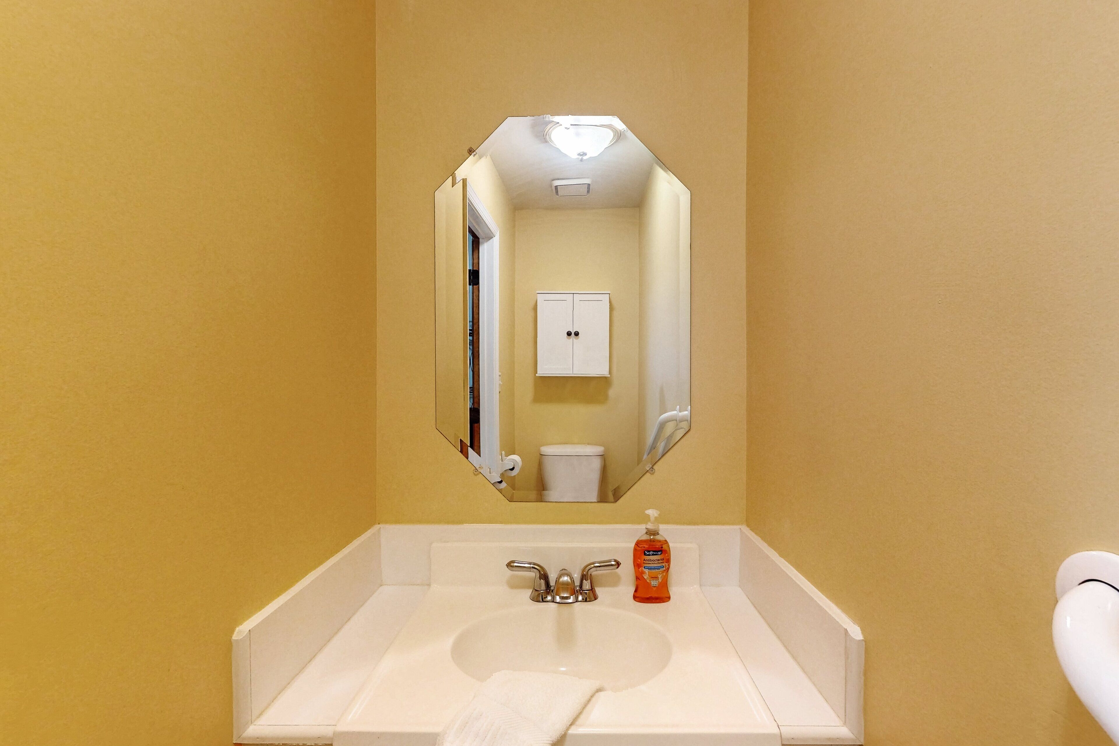 Un baño con un lavamanos blanco, un espejo, un inodoro y una toalla.