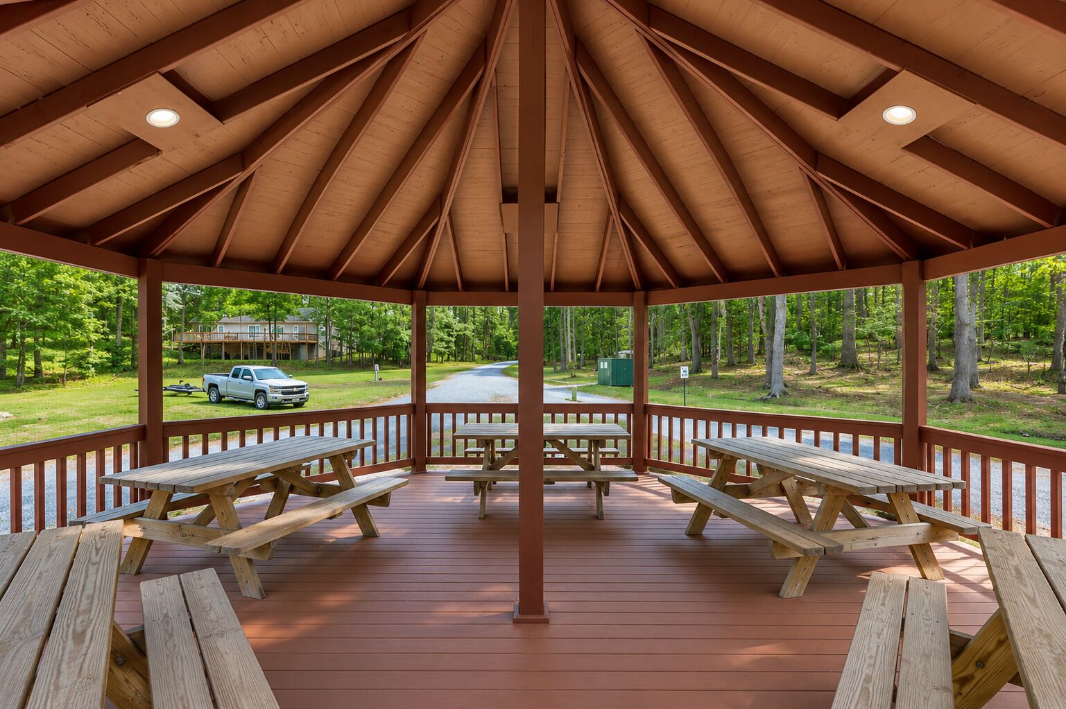 Un pavillon abrité avec des tables de pique-nique, une vue sur une route et un véhicule en arrière-plan.
