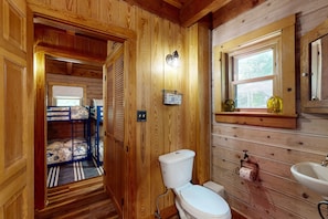 Ein Holzinnenraum mit einem Etagenbett, Toilette, Waschbecken und einem Fenster mit Blick.