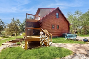 A log cabin with a wooden deck, a staircase, and a bench.