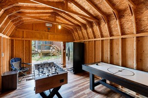 An indoor recreational area with a foosball table, a pool table, and a seating area.