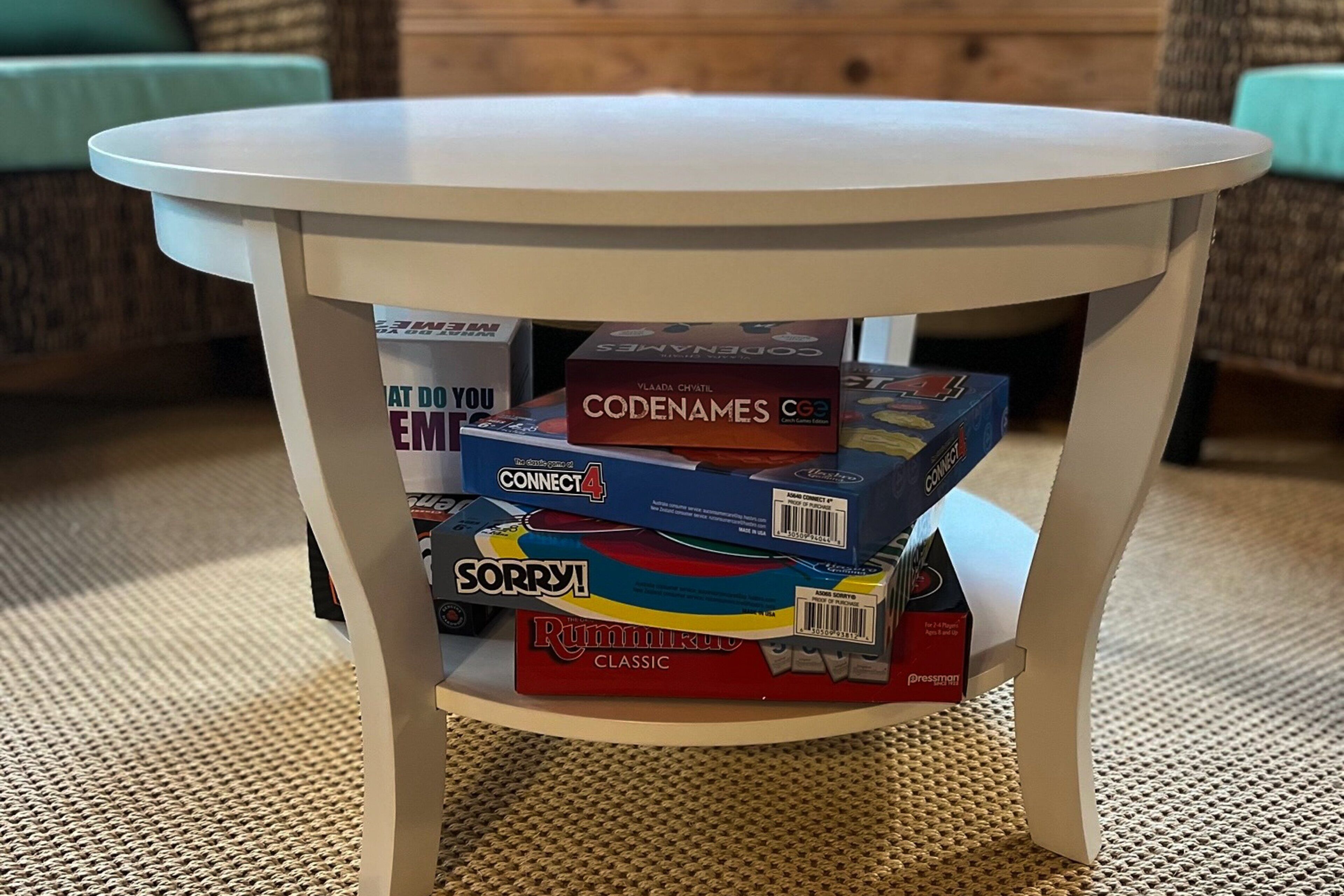 Une table ronde avec un plateau blanc et quatre jeux de société empilés dessus.