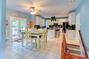 A spacious kitchen with white cabinets, a dining area with a glass table, and a ceiling fan. - Lakefront Home With Boat Dock, Private Firepit & Game Room - Dog-friendly (Bumpass)