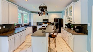 A spacious kitchen with white cabinetry, a central island, and a hanging pot rack. - Lakefront Home With Boat Dock, Private Firepit & Game Room - Dog-friendly (Bumpass)