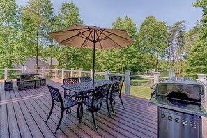 A deck with a table and chairs, a grill, and a view of a lake. - Lakefront Home With Boat Dock, Private Firepit & Game Room - Dog-friendly (Bumpass)