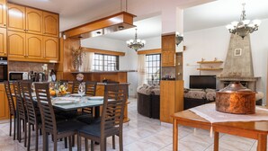 Una cocina moderna con armarios de madera, una mesa de comedor preparada para cuatro comensales y una olla de cobre grande sobre una mesa.