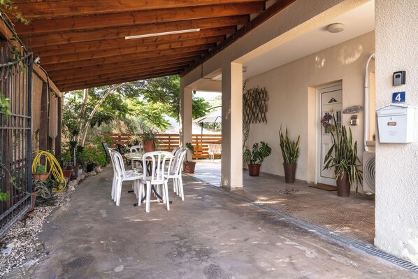 A covered patio area with a table and chairs, potted plants, and a door marked with the number 4.