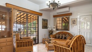 Una habitación con muebles de mimbre, una araña y ventanas grandes.