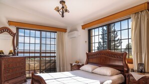 Un dormitorio con una cama grande, cómoda de madera y una ventana con cortinas.