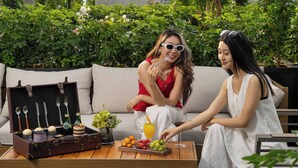 A rooftop terrace with a wooden table, two sofas, and a backdrop of greenery and city buildings. - Wanda Moments Zhuhai (Zhuhai)