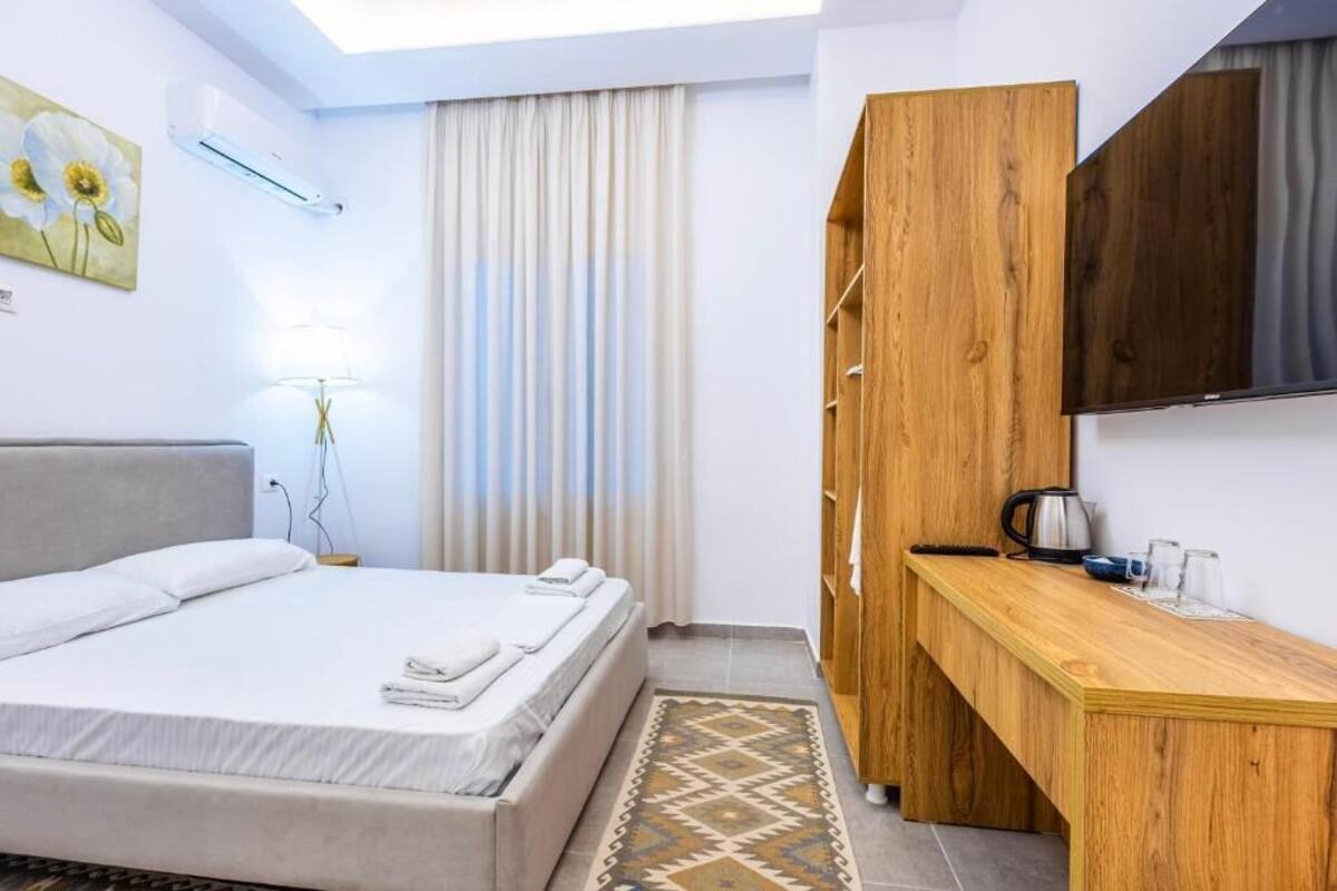 Ein Hotelzimmer mit Bett, Schreibtisch aus Holz, Fernseher und einem Fenster mit Vorhängen.