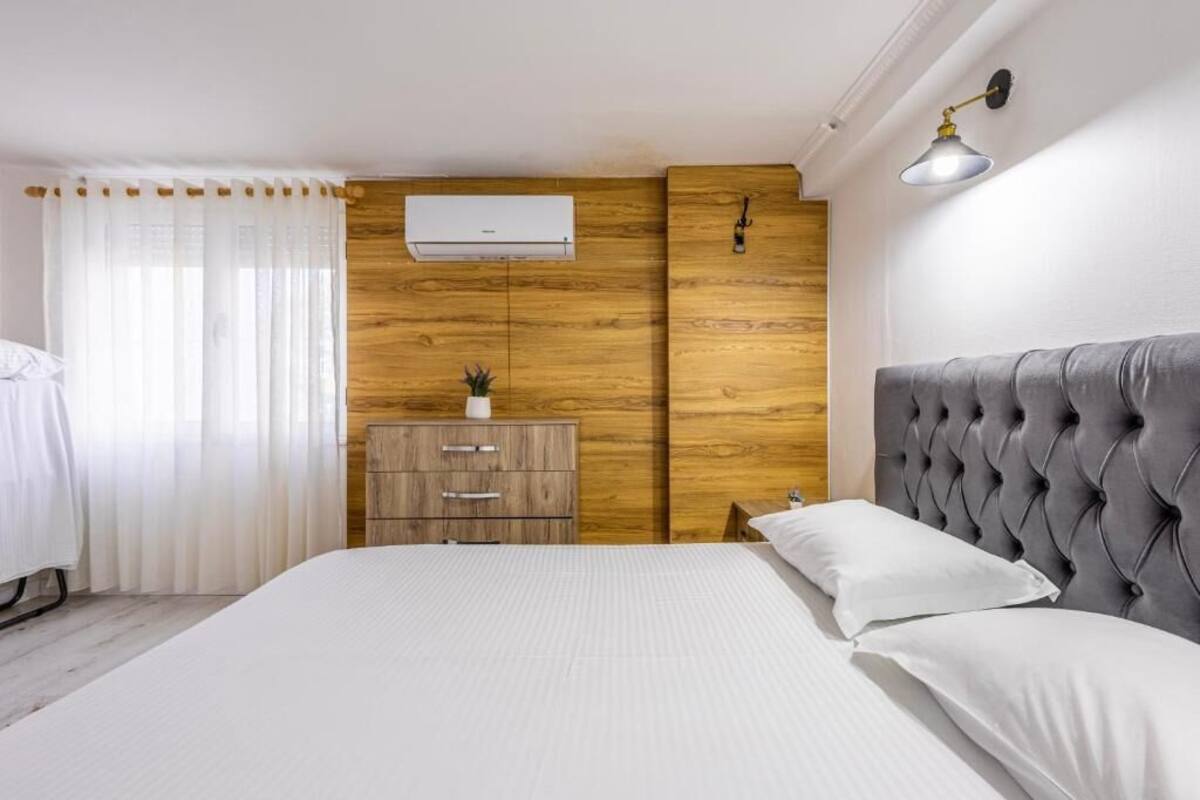 Ein Schlafzimmer mit einem Bett, einer Holzkommode, einer Wandklimaanlage und einer Nachttischlampe.