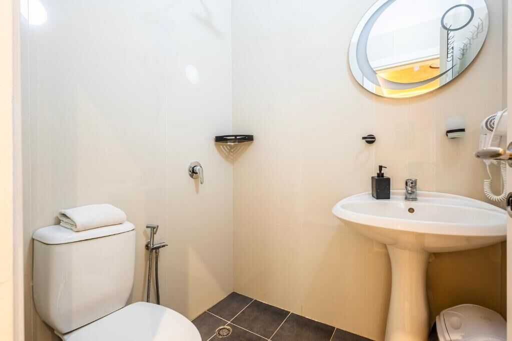 A bathroom with a toilet, sink, mirror, and shower.