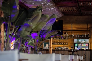 A bar area with a wooden ceiling, shelves with bottles, and a sign for 'Cuvée'. - LaLun Apartments & Rooms (Golem)
