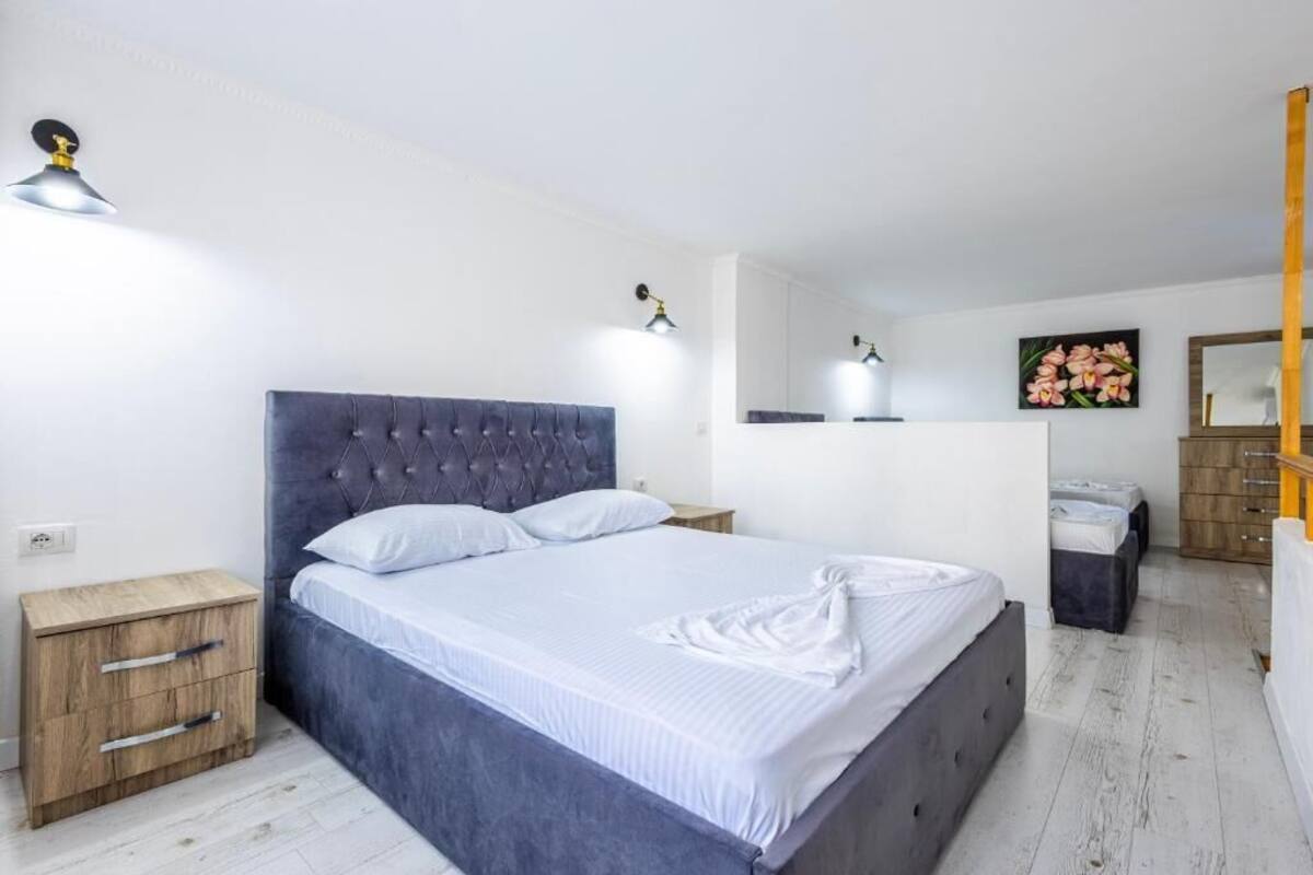 Ein Schlafzimmer mit einem großen Bett, Nachttischen, einem Kleiderschrank und einem Spiegel.