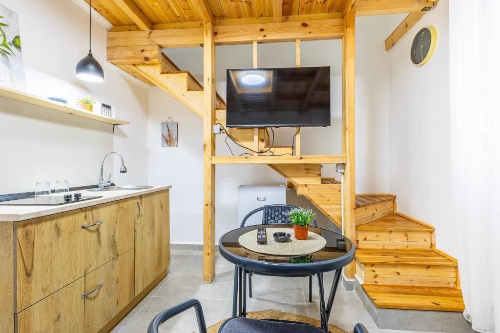 Een kleine keuken met houten kastjes, een eettafel en een televisie bevestigd aan een houten balk.